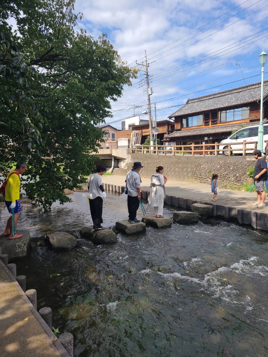 川辺の飛び石を渡る人たち